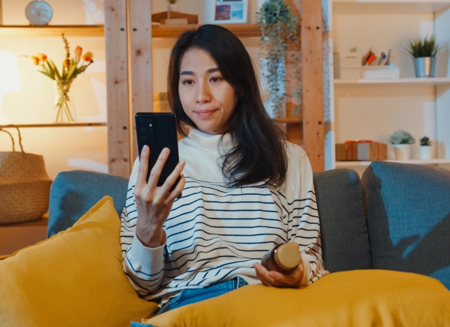 Person holding phone close to face with a pill bottle in other hand.
